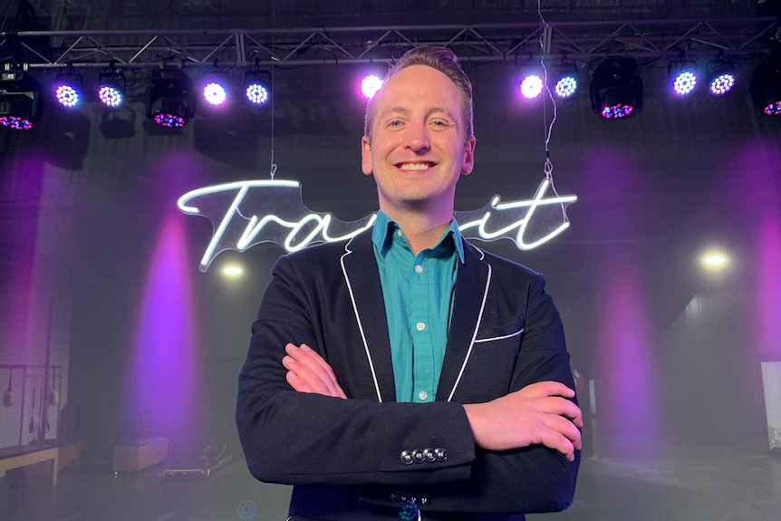 Man stands in front of neon sign saying 'Transit'