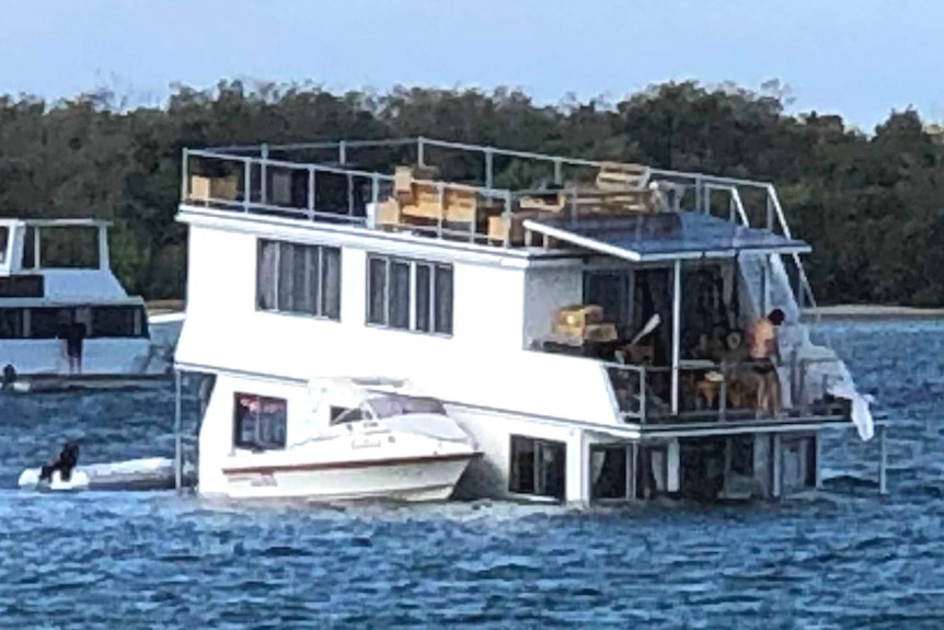 A houseboat lopsided as it becomes partially submerged