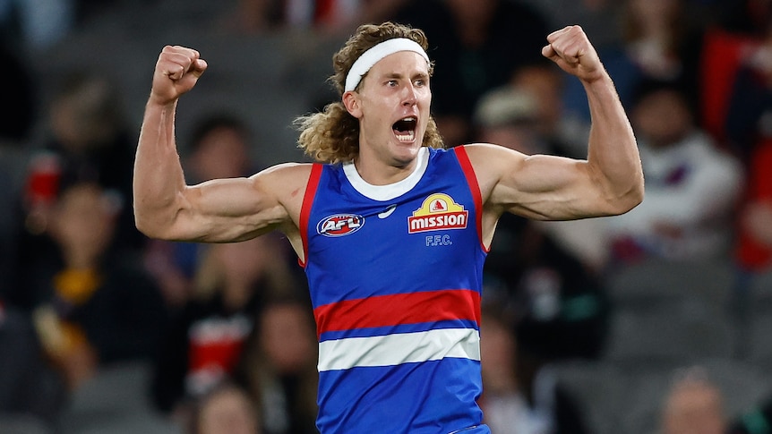 Aaron Naughton of the Western Bulldogs flexes with both arms, celebrating a goal