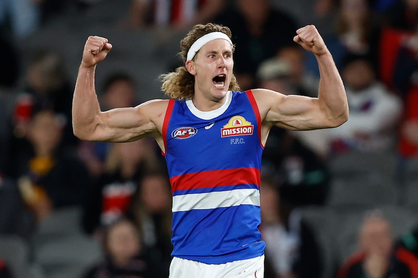 Aaron Naughton of the Western Bulldogs flexes with both arms, celebrating a goal