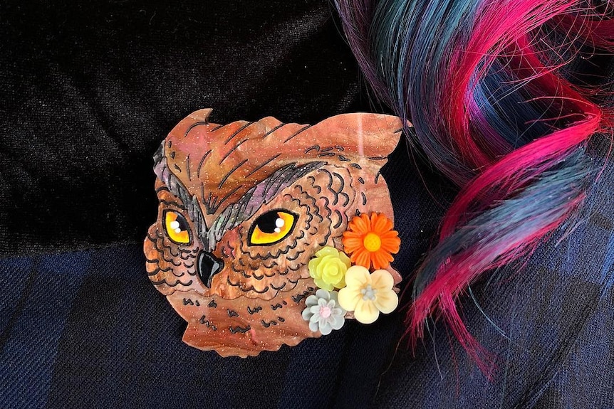 Woman with blue and pink hair wearing owl brooch