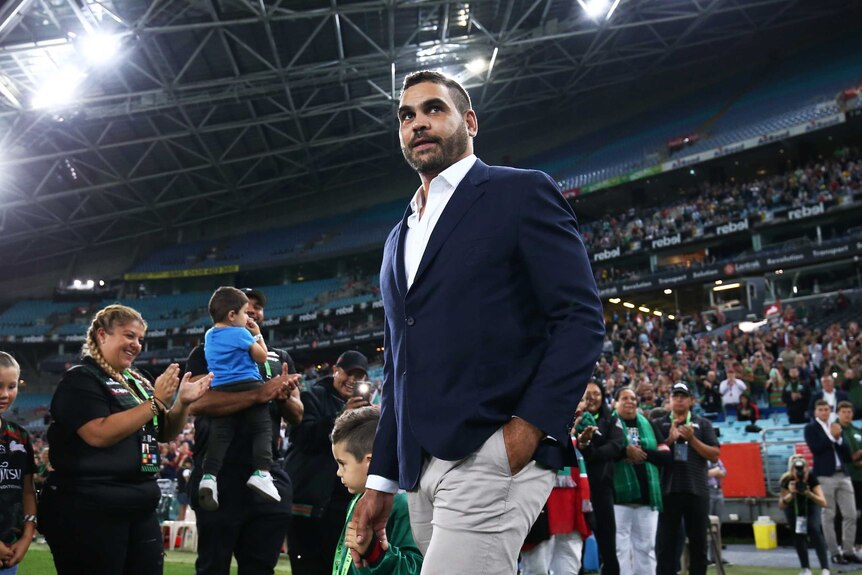 Greg Inglis walks onto the Olympic stadium ground as family and friends forma guard of honour.