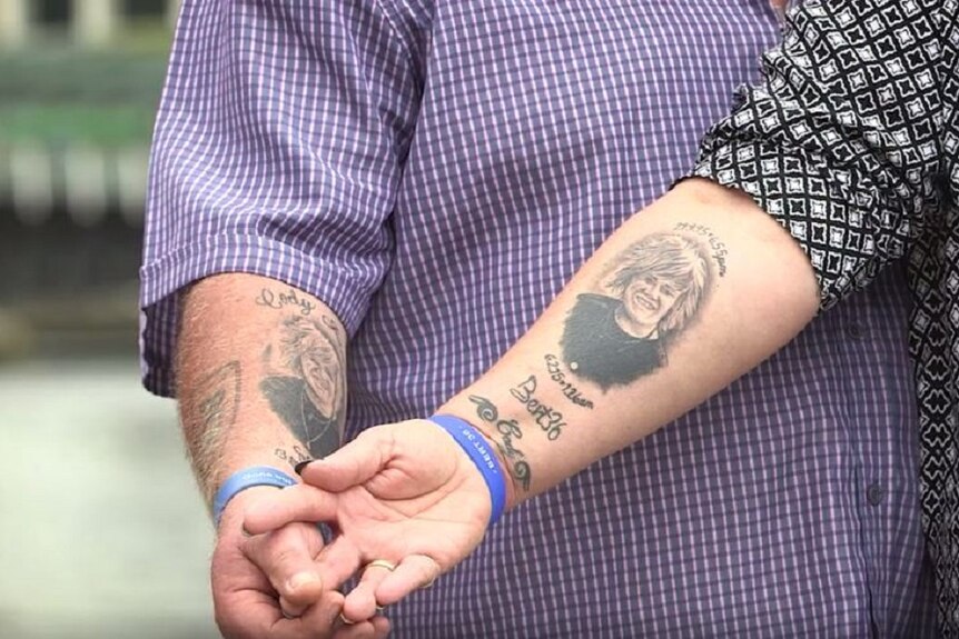 Father and mother show tattoos of pictured of dead son's face with his name, birth and death date on their inner lower arm.