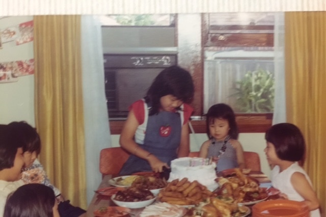 Hetty McKinnon cuts into a birthday cake surrounded by other children, and a table full of meat before she became a vegetarian.