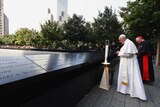 Pope Francis pauses in front of a candle to pray with Timothy Cardinal Dolan while visiting the 9/11 Memorial plaza in New York.
