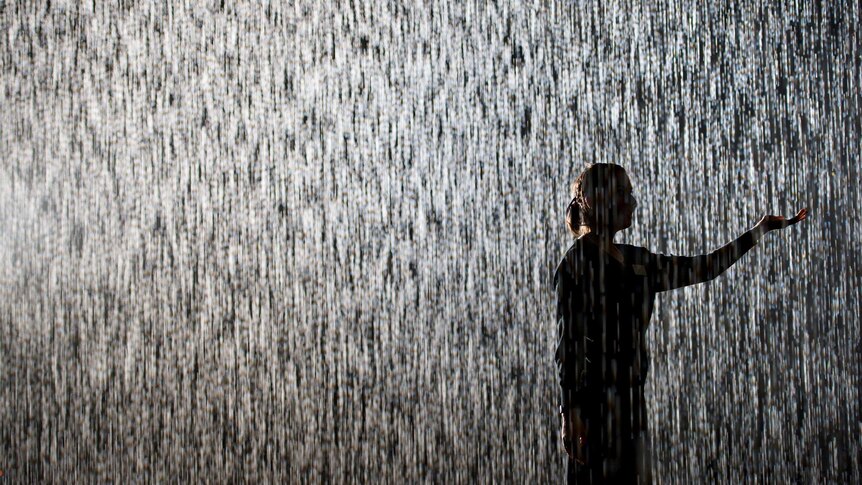 A woman stands in the Rain Room at the Barbican in London.
