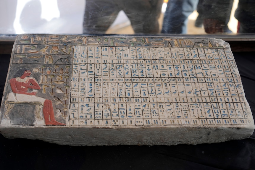 A rock slab featuring heiroglyphics and Egyptia art sits on display. 