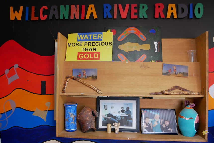 A wall-mounted shelf containing decorations and a sign that says "Water: More Precious Than Gold".