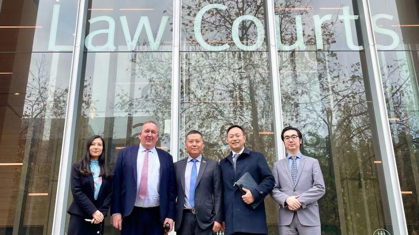 Five people stand smiling outside the Supreme Court. 