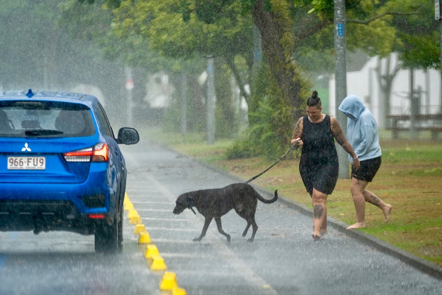 Two people trying to get out of the rain beside a road in Cairns. 