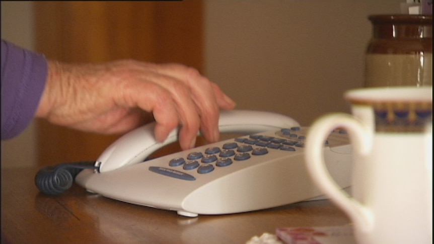 An older person uses a landline telephone