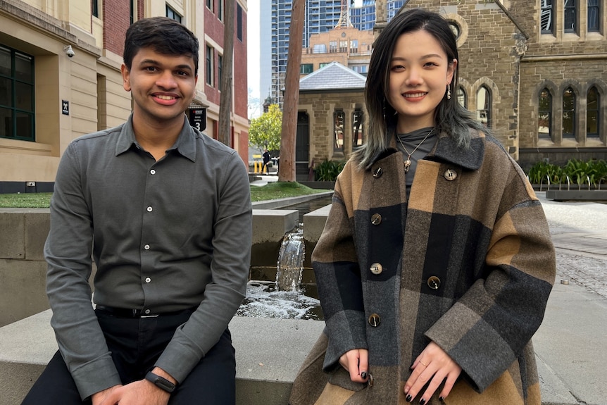 Bhavya Bagaria and Jinru Sun sit beside a water feature on campus at RMIT