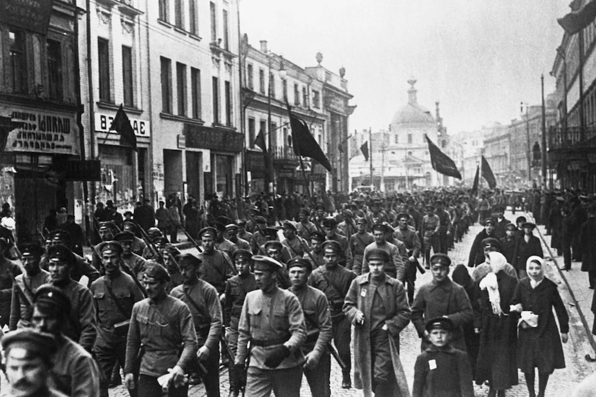 Black and white photo of soldiers marching down a street.