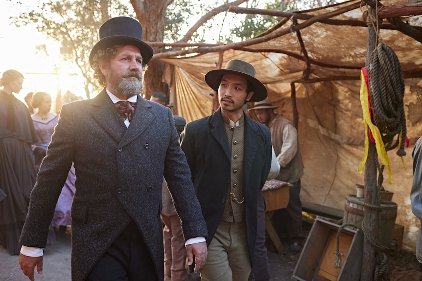 Two actors dressed in 1850s costumes in a mining camp.