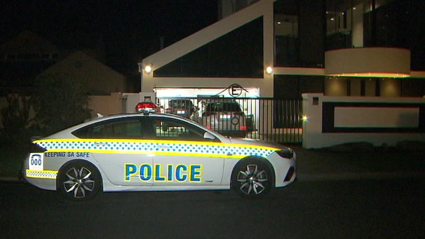 A police car at night in front of a large house