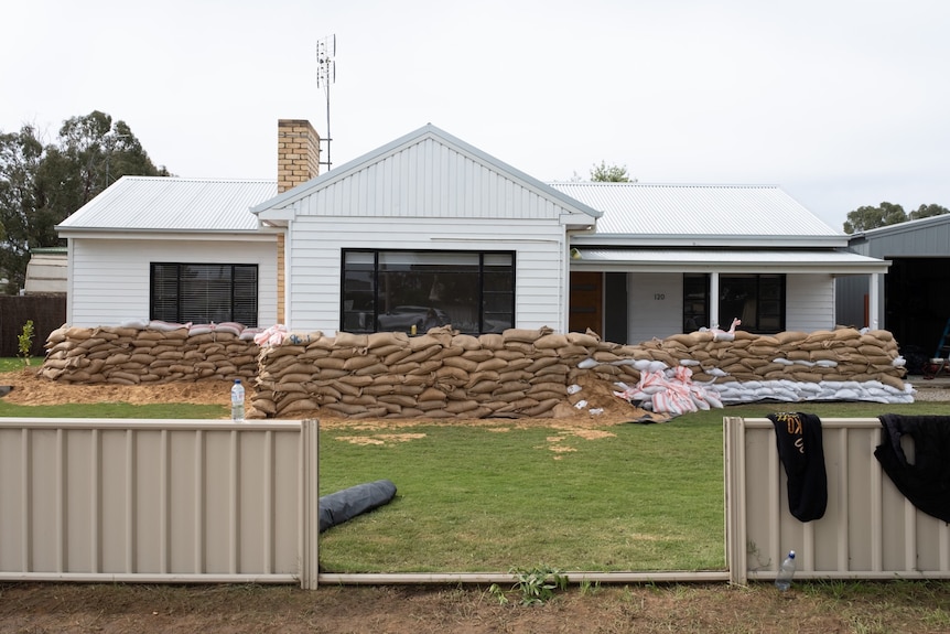 A large pile of sandbags outside a weatherboard home.