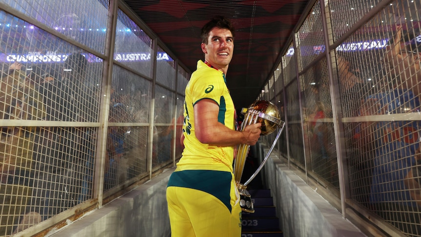 Pat Cummins looks back over his shoulder while holding the World Cup trophy