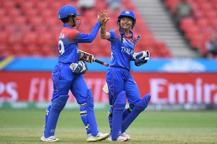 Two Thailand batters give each other a high five as they leave the field in the T20 World Cup match in Sydney.