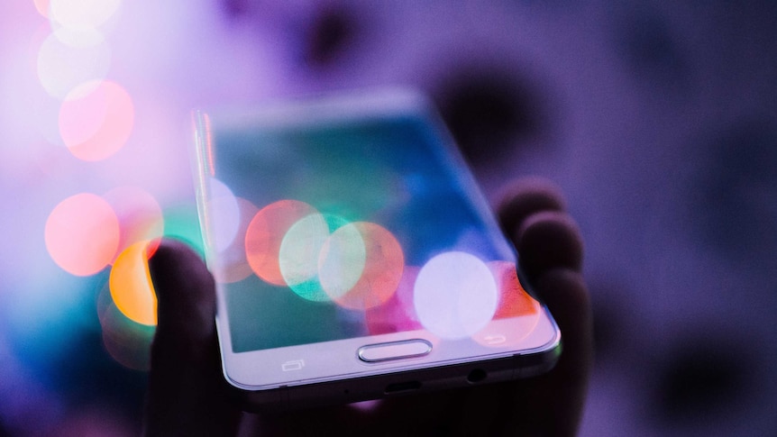 A hand holding a white smartphone