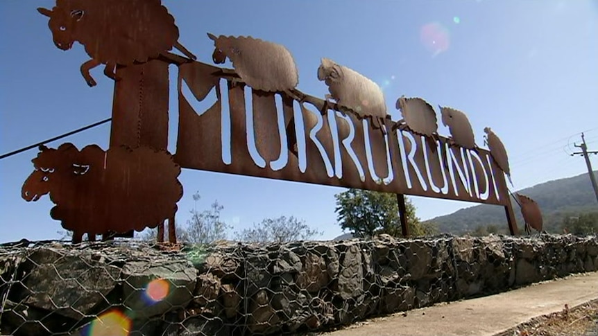 An iron sign with the letters of Murrurundi cut out and the blue shining through, surrounded by carved flat sheep sculptures.
