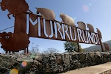 An iron sign with the letters of Murrurundi cut out and the blue shining through, surrounded by carved flat sheep sculptures.