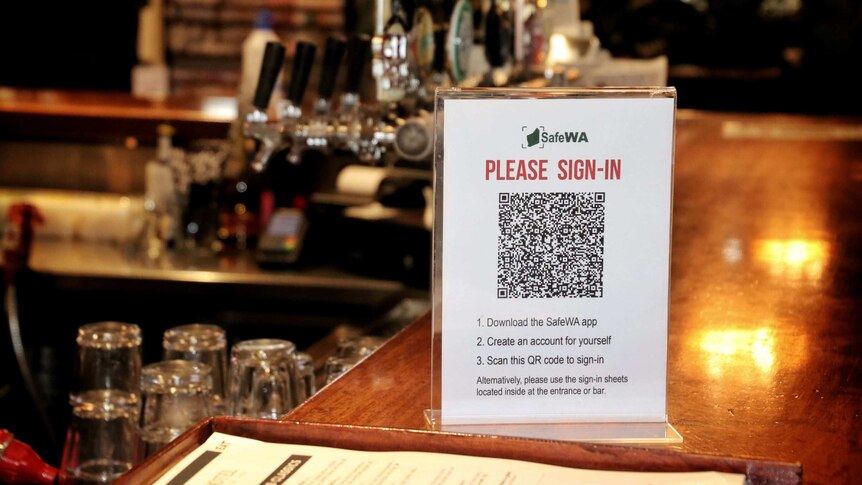 A sign saying 'please sign in' with a QR code on it on a bar.
