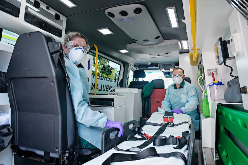 Emma Johnson and Steven Schrieke, from St John Ambulance NT, are inside an ambulance wearing PPE.
