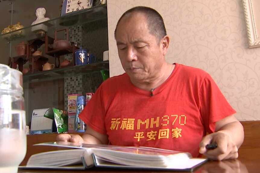 Wen Wancheng looks at a photo album of his son Wen Yongsheng.