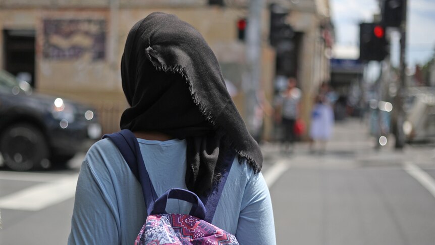 A girl wearing a hijab waits to cross the road in Melbourne.