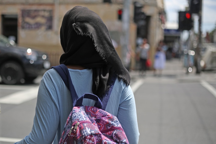 A girl wearing a hijab waits to cross the road in Melbourne.