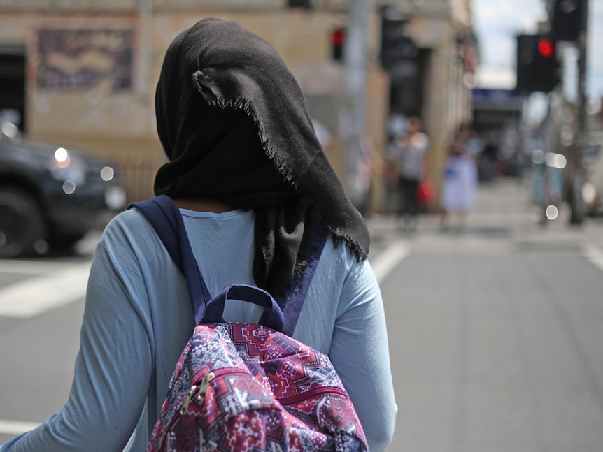 A girl wearing a hijab waits to cross the road in Melbourne.