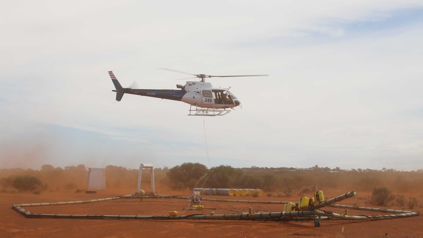 A helicopter hovers above a giant electro-magnet