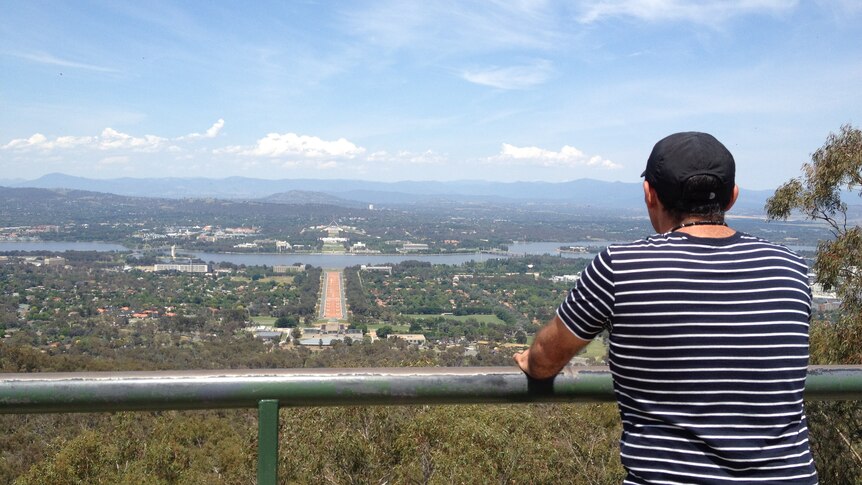 A tourist admires the view of Canberra from Mount Ainslie