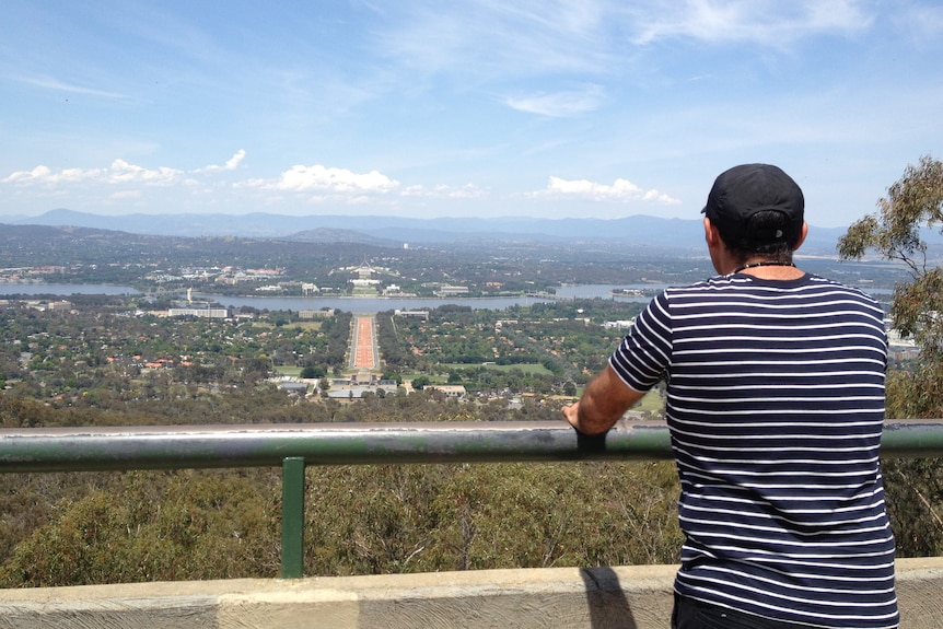 A tourist admires the view of Canberra from Mount Ainslie