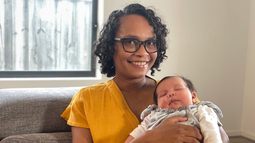 A woman on a couch holding her baby 