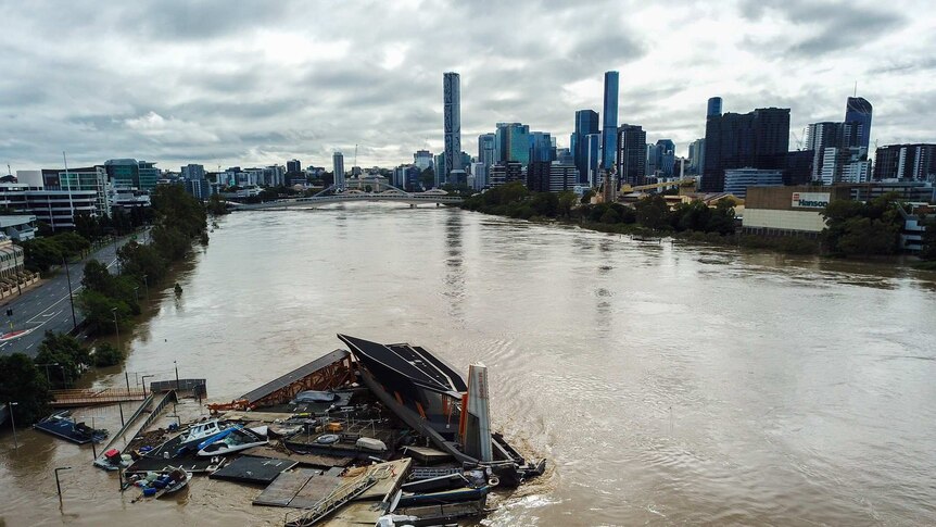 A crane floats down the Brisbane river on a pontoon as the river rises again.