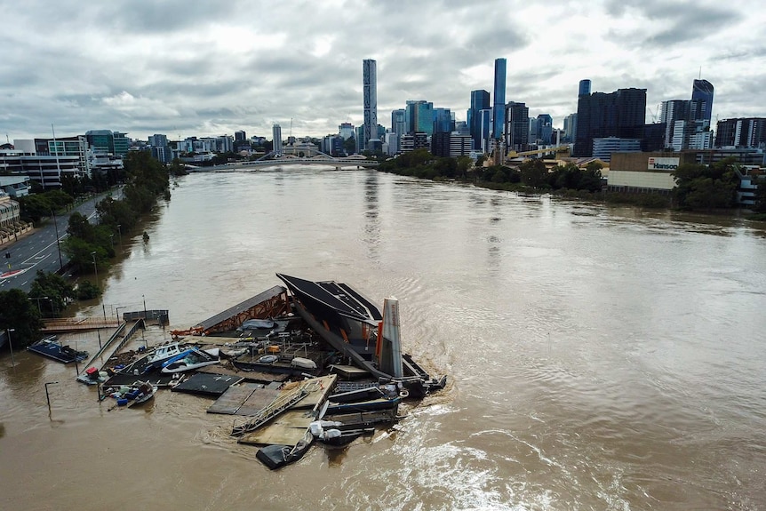 A crane floats down the Brisbane river on a pontoon as the river rises again.