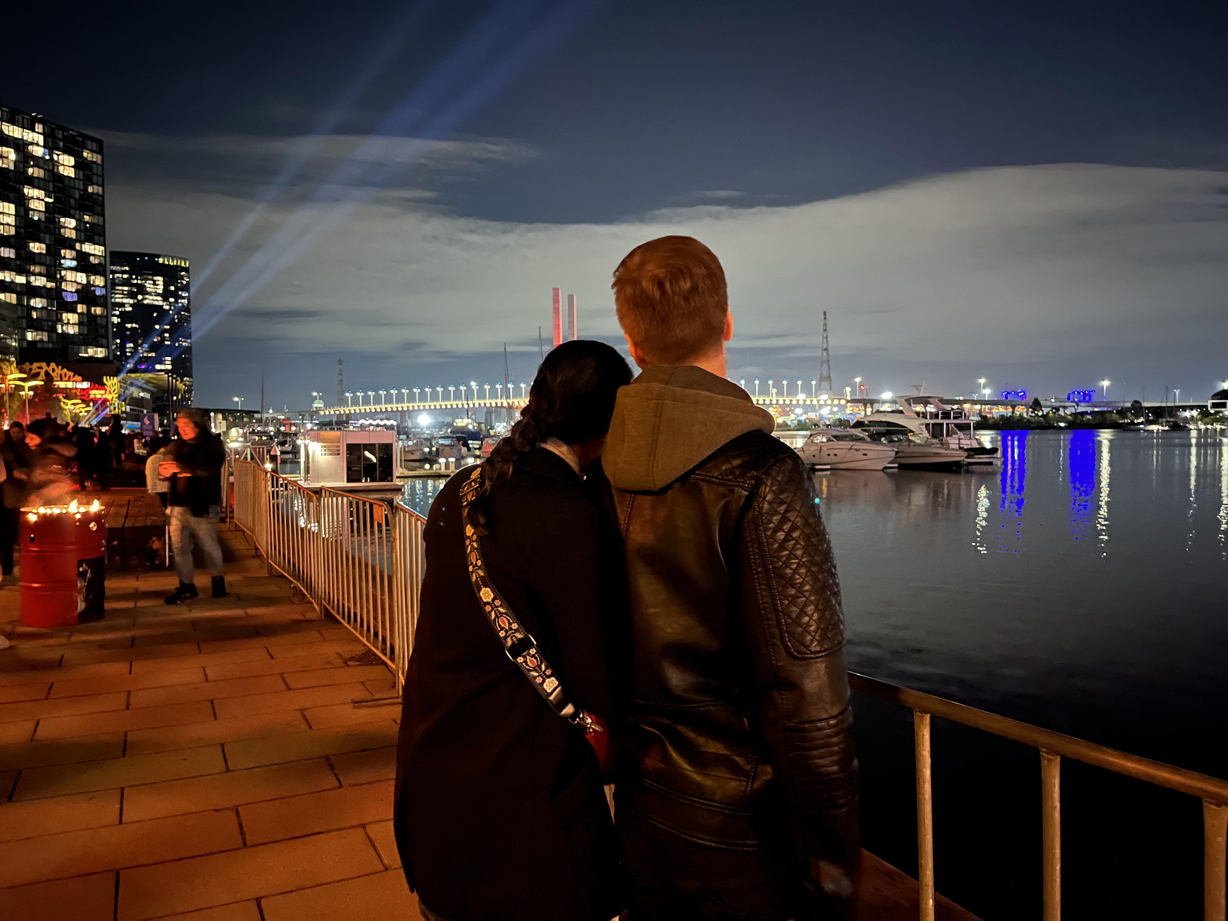 A couple looking out at a waterfront at night