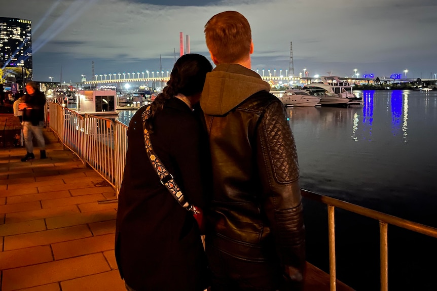 A couple looking out at a waterfront at night
