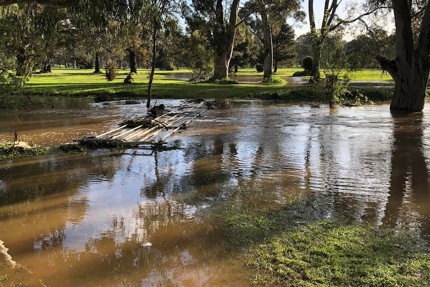 A footbridge is covered by water on a flooded golf course.