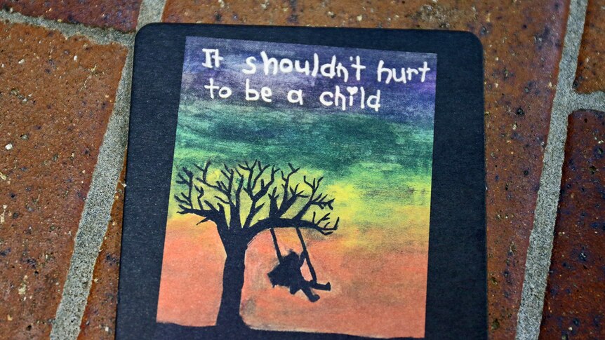 'It shouldn't hurt to be a child' painted on a coaster