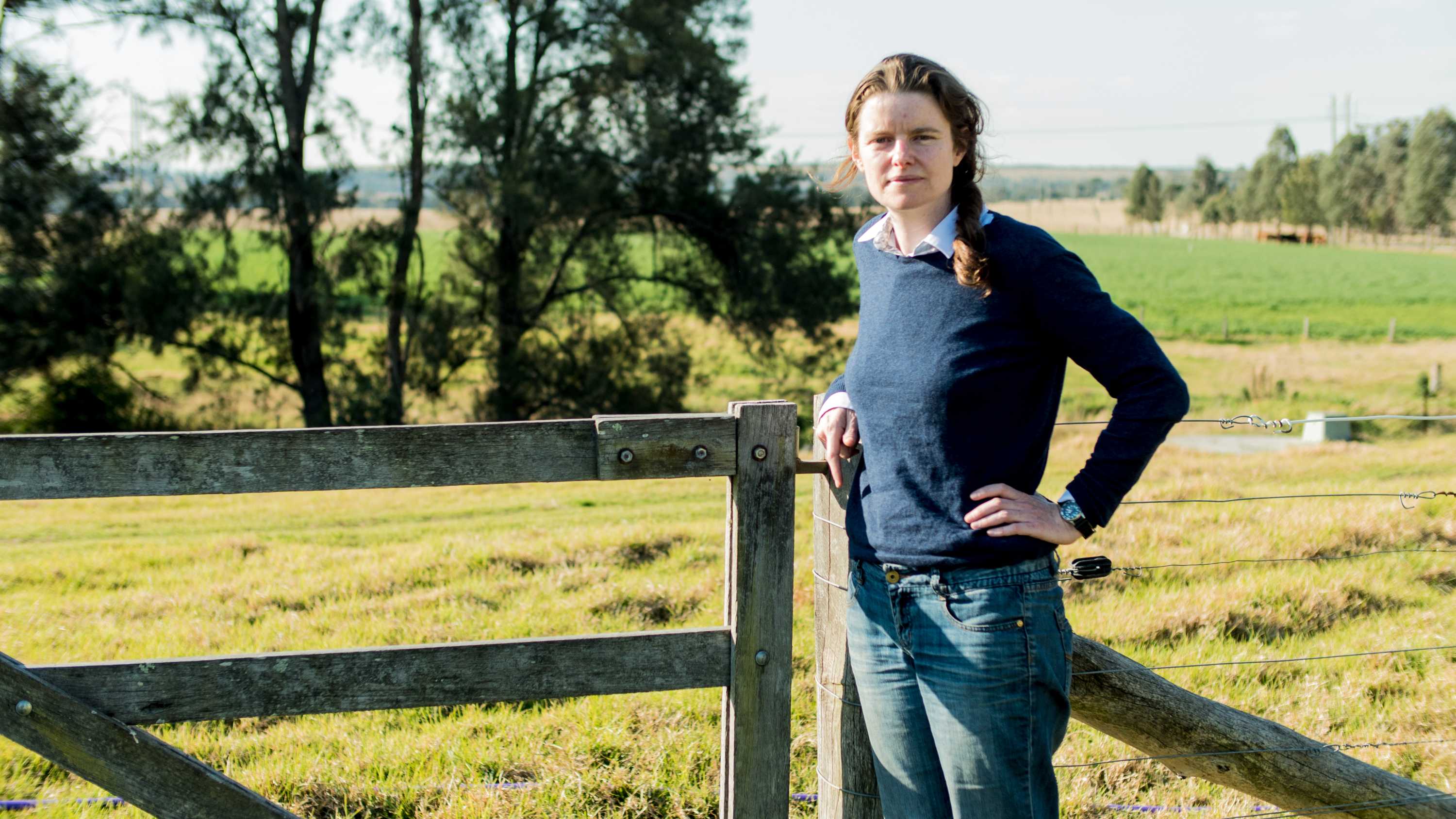 Georgina Woods leans against a fence in the countryside