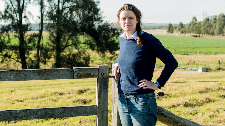 Georgina Woods leans against a fence in the countryside