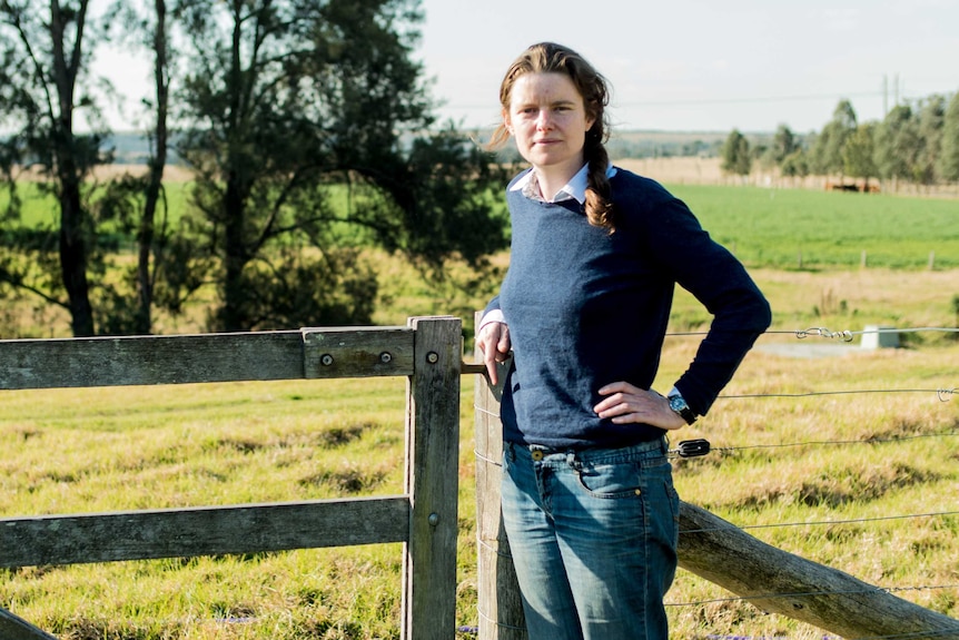 Georgina Woods leans against a fence in the countryside