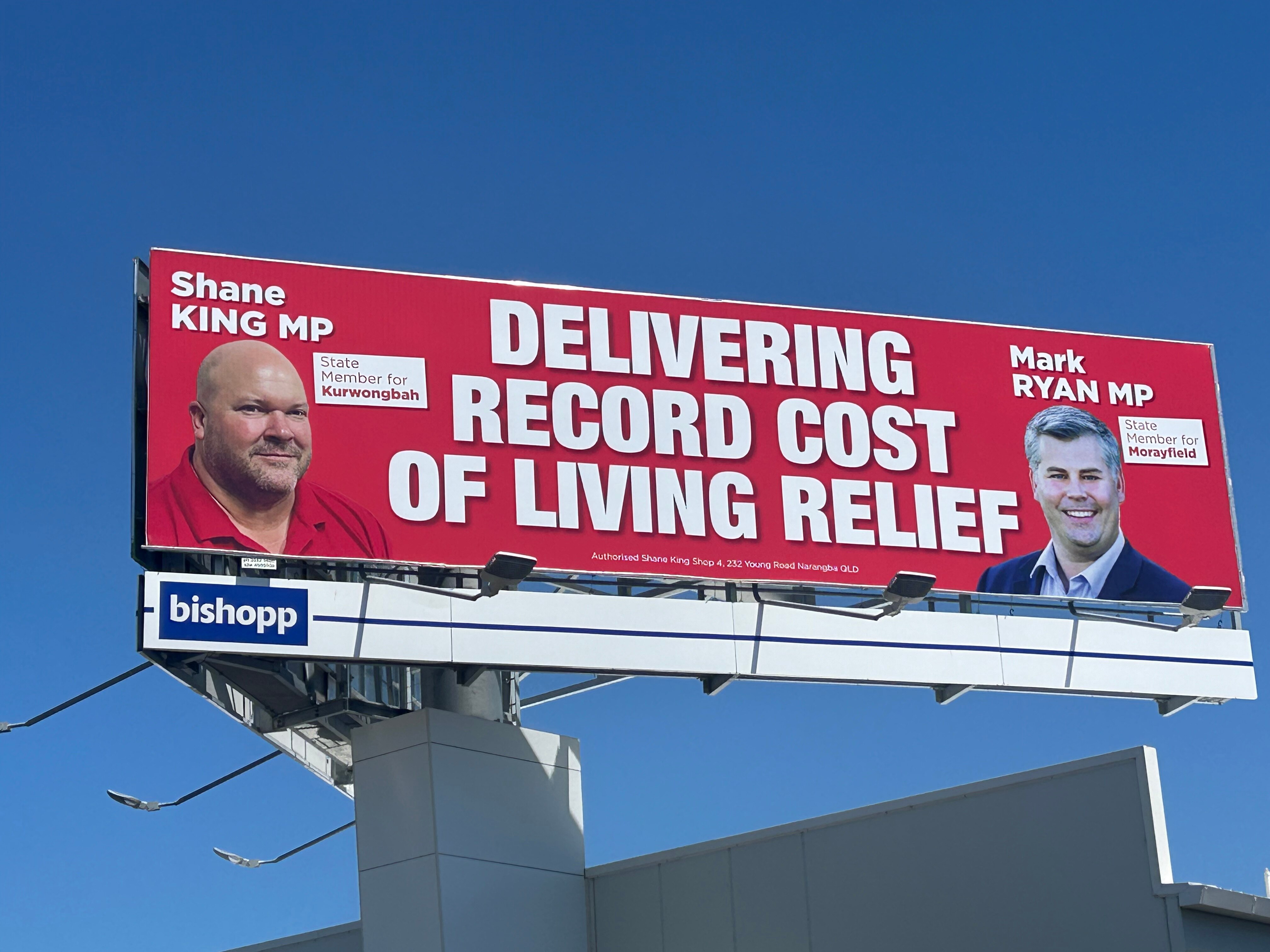 A red billboard featuring images of Shane King MP and Mark Ryan MP.