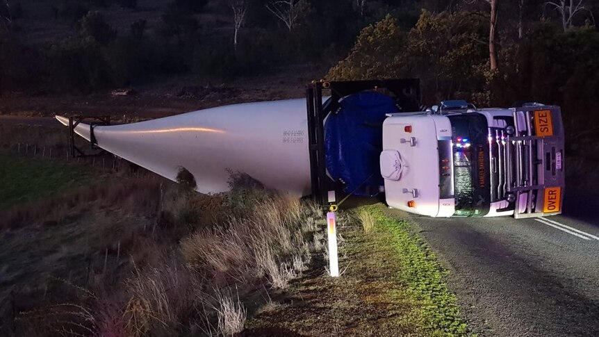 A rolled over truck carrying an 80-metre wind turbine blade.