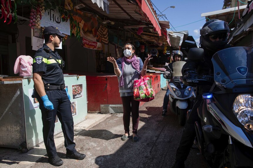 A woman argues with a p0olice officer in front of a food market.