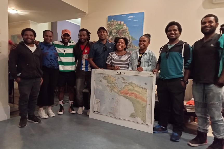 A group of West Papuan students standing with a large map.
