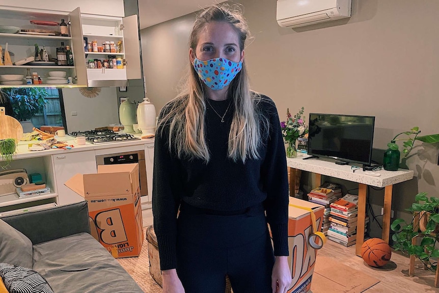 a woman with a mask on surrounded by moving boxes