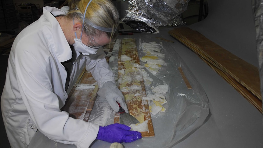 A police member removes ice from wooden floorboards.